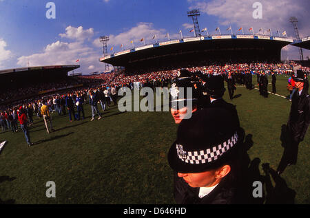 Archiv: Hillsborough Katastrophe 15. April 1989 FA Cup-Halbfinale-Liverpool V Nottingham Forest. Polizisten im Vordergrund als Fans sind abgebildet unter Werbung Hordings vom Ende Kop, Unterstützer in der Leppings Lane Ende (ganz links) zu helfen. Das FA-Cup-Halbfinale zwischen Liverpool und Nottingham Forest wurde nach sechs Minuten des Spiels abgebrochen. in der Katastrophe starb 96 Fans in Liverpool Ende in der Leppings Lane, erdrückt. South Yorkshire Polizei war im Einsatz auf dem Spiel. Gespielt wurde in der neutralen Zone von Hillsborough, Sheffield-Wednesd-home Stockfoto