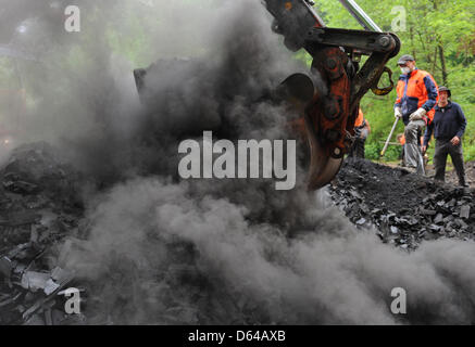 Ein Bagger öffnet eine Kohle Grube in Freiburg, Deutschland, 24. Mai 2012. Die Grube hatte vor vier Wochen mit 45 Kubikmetern Holz gefüllt wurde. Nach der Eröffnung am 24. Mai sind vier Tonnen Kohle das erwartete Ergebnis. Foto: Patrick Seeger Stockfoto