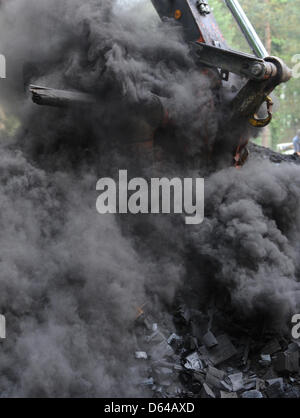 Ein Bagger öffnet eine Kohle Grube in Freiburg, Deutschland, 24. Mai 2012. Die Grube hatte vor vier Wochen mit 45 Kubikmetern Holz gefüllt wurde. Nach der Eröffnung am 24. Mai sind vier Tonnen Kohle das erwartete Ergebnis. Foto: Patrick Seeger Stockfoto