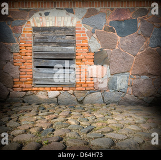 Alte Steinmauer und Fenster mit hölzernen Planken bedeckt Stockfoto