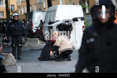 Polizisten klar Bereich der Barrikaden, während zwei Frauen um einen verletzten Mann kümmern, die gegen eine Neonazi-Kundgebung unter dem Motto "Tag der deutschen Zukunft" in Hamburg, Deutschland, 2. Juni 2012 protestierten. Mehrere tausend Menschen demonstrierten gegen den Marsch der Rechtsextremisten. Foto: Christian Charisius Stockfoto