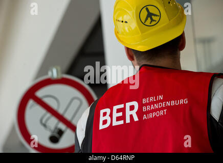 Ein Bauarbeiter blickt auf ein Rauchverbot, das Zeichen am Terminal des neuen Hauptstadt-Flughafens Berlin Brandenburg Willy Brandt (BER) in Schönefeld, Deutschland, 30. Mai 2012 abgebildet sind. Foto: Patrick Pleul Stockfoto