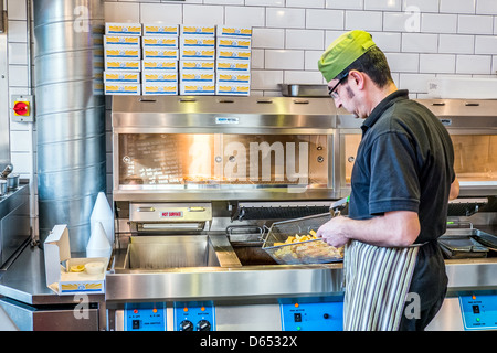 Ein Mann Kochen Fish &amp; Chips in einem traditionellen britischen Fish &amp; Chips-shop Stockfoto