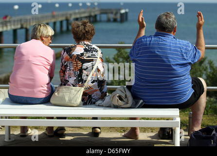 Ein übergewichtiger Mann sitzt neben zwei ältere Frauen auf einer Bank an der Strandpromenade an der Ostsee-Küste in Ostsee, Deutschland, 15. Juni 2012. Die Strände an der Ostsee sind bei Senioren beliebt, während die vor und nach Jahreszeiten. Foto: Jens Büttner Stockfoto