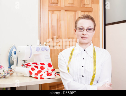 lächelnde Schneiderin in einem Arbeitsraum Stockfoto