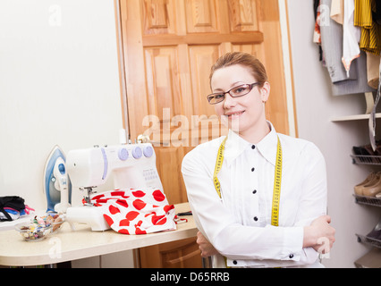 lächelnde Schneiderin in einem Arbeitsraum Stockfoto