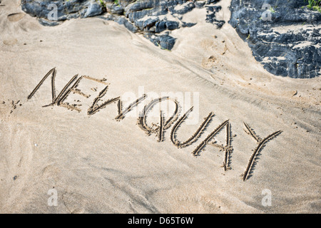 Das Wort Newquay geschrieben im Sand am Strand Stockfoto