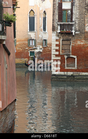 Ein Gondoliere und seine Gondel auf einer kleinen Nebenstraße Kanal mit bunten Altbauten in Venedig Italien Stockfoto