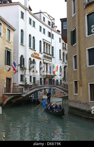 Ein Gondoliere und seine Gondel auf einer kleinen Nebenstraße Kanal mit den bunten alten Gebäuden des Hotel Colombina in Venedig Italien Stockfoto