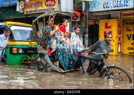 Fahrradrikscha, und Auto-Rikscha und Passagiere in schweren Monsunregen und Sturzflut, Varanasi, Indien gefangen. Stockfoto