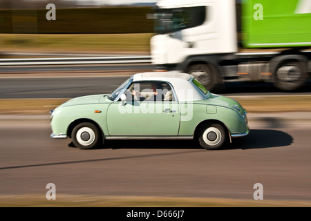 Retro-60er Jahre Stil Nissan Figaro japanisches Auto überholt von einem LKW auf der Schnellstraße in städtischen Dundee, Großbritannien Stockfoto