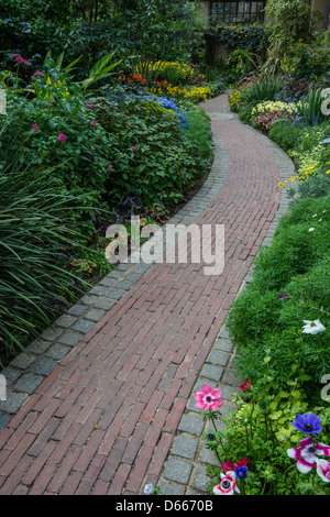 Ziegelsteinweg durch Blumengarten Stockfoto