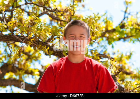 Teenager oben im Baum glücklich und lächelnd. Stockfoto