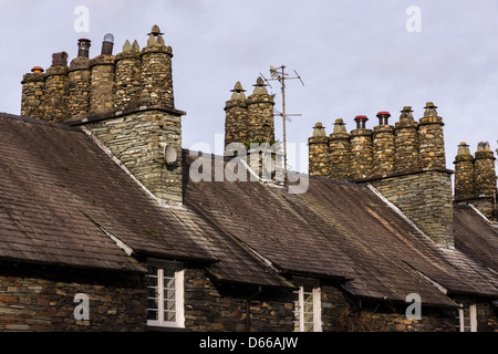 Schieferschornsteine, quadratische Schornsteine und runde Töpfe über terrassenförmig angelegten Lageland Cottage Dächern, Skelwith, Cumbria, England, Großbritannien Stockfoto