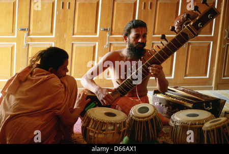 Ein hinduistischer Mönch ("Sadhu") spielt Sitar, während ein Neuling hört. Beide gehören der Swaminarayan-Sekte (Indien) Stockfoto