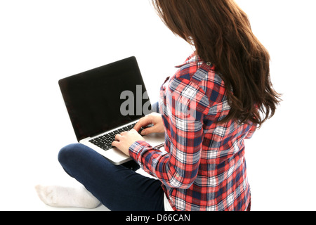 Junge Frau, die allein auf dem Boden sitzt und mit EINEM Laptop arbeitet, arbeitet remote zu Hause im Internet und isoliert von Coronavirus Stockfoto