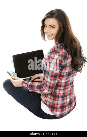 Junge Frau, die allein auf dem Boden sitzt und mit EINEM Laptop arbeitet, arbeitet remote zu Hause im Internet und isoliert von Coronavirus Stockfoto