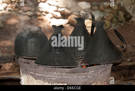 Schwarzer Kessel zum Kochen von Wasser am offenen Feuer Stockfoto