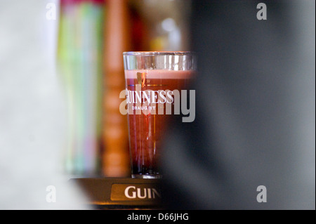 Ein bedrucktes Glas Pint Guinness an der Bar pub Tabelle getränke Gläser Stockfoto