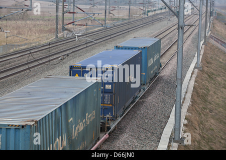 Container Fracht Reisen entlang der West Coast Mainline Railway durch die Midlands. Intermodaler Verkehr genannt. Stockfoto