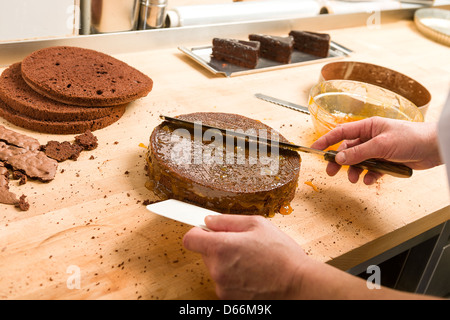 Kochen Sie sich ausbreitenden Sauce auf Kuchen mit Messer in der Küche Stockfoto