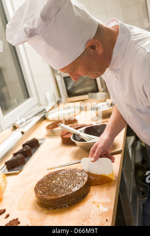 Männlichen Chef Verbreitung Aprikose Marmelade i-Tüpfelchen in Küche Stockfoto