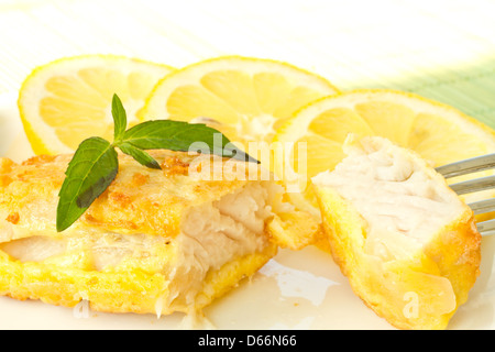 Fischfilets gebraten in Teig mit Zitrone und Basilikum auf einem Teller Stockfoto