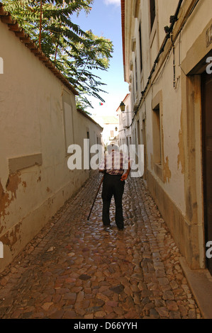 Älterer Mann zu Fuß entlang der gepflasterten Backstreet im Süden Portugals Algarve Stockfoto