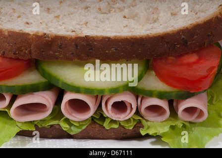 Sandwich mit Multi-Korn-Brot mit Schinken, Salat, Tomaten und Gurken isoliert auf weißem Hintergrund, Vorderansicht Stockfoto