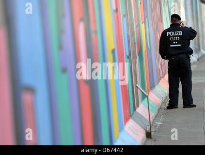 Berlin, Deutschland. 14. April 2013. Ein Polizist steht neben der East Side Gallery. Ein Investor plant ein Hochhaus Wohnhaus auf einem Grundstück neben der Spree. Foto: BRITTA PEDERSEN/Alamy Live-Nachrichten Stockfoto