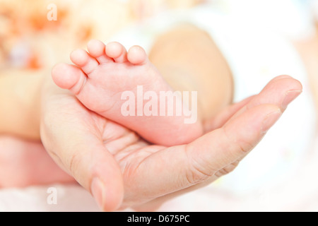 Füße von Neugeborenen in Händen der Mütter Stockfoto