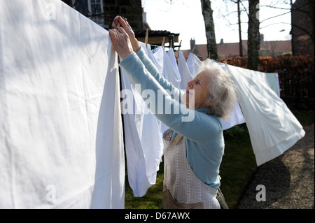 Ältere Rentner eine Linie des Waschens auf ihrer Wäscheleine im April hängen. Stockfoto