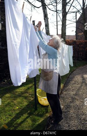 Ältere Rentner eine Linie des Waschens auf ihrer Wäscheleine im April hängen. Stockfoto