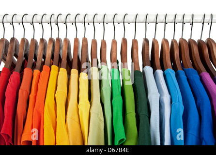 Farben des Regenbogens. Auswahl an Freizeitkleidung auf Holzbügel, isoliert auf weiss. Stockfoto