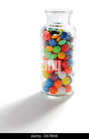 Glasflasche mit Schokolinsen Stockfoto