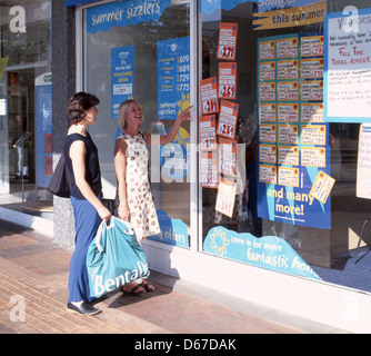 Junge Frauen auf der Suche in Reisebüros Fenster, Bracknell, Berkshire, England, Vereinigtes Königreich Stockfoto