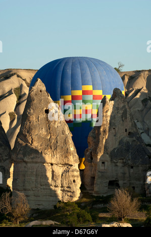 Heißluft-Ballon-Manöver zwischen Tuff-Felsen-Kegeln in den Felsen von Kappadokien, Göreme, Türkei Stockfoto