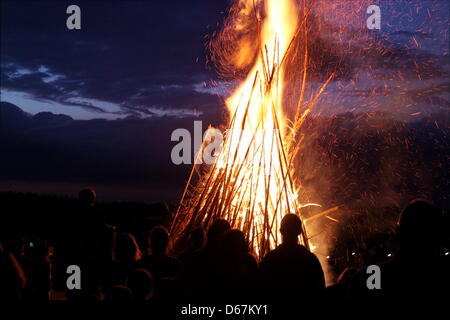 Menschen stehen vor einer riesigen Johanniskraut Lagerfeuer in Baierbrunn, Deutschland, 22. Juni 2012. Das Fest des Hl. Johannes deckt sich mit der Juni-Sonnenwende auch als Mittsommer bezeichnet. Foto: Stephan Jansen Stockfoto