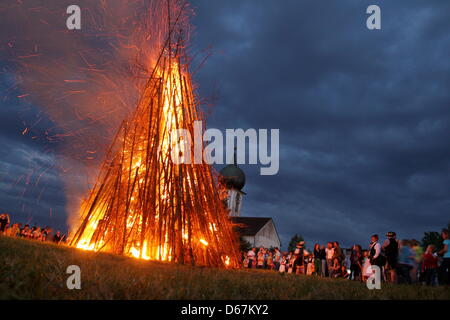 Menschen stehen vor einer riesigen Johanniskraut Lagerfeuer in Baierbrunn, Deutschland, 22. Juni 2012. Das Fest des Hl. Johannes deckt sich mit der Juni-Sonnenwende auch als Mittsommer bezeichnet. Foto: Stephan Jansen Stockfoto