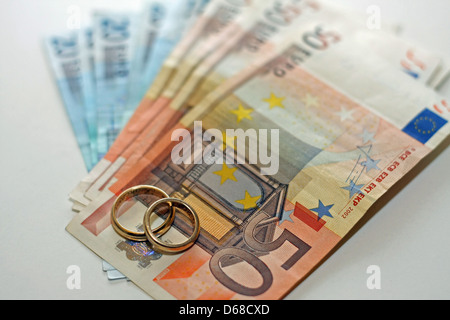 Geld und Euro-Banknoten mit zwei Trauringe in Gold stehen ganz oben auf dem Stapel Stockfoto