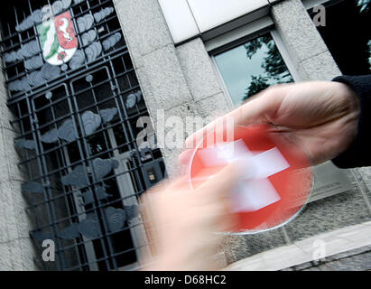 ILLUSTRATION - In einer inszenierten Szene wird eine CD mit einer Schweizer Flagge bedruckt ist vor dem Finanzministerium in Düsseldorf, Deutschland, 15. Juli 2012 übergeben. Die angebliche Übernahme durch die deutschen Bundesland Nordrhein Westfalen eine andere CD aus der Schweiz mit reichen Germans  Bankverbindung als Teil der Bemühungen um Steuerhinterzieher zu identifizieren hat die Schweizer verärgert. Schweizer Stockfoto