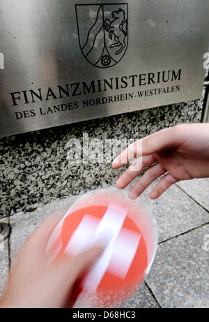 ILLUSTRATION - In einer inszenierten Szene wird eine CD mit einer Schweizer Flagge bedruckt ist vor dem Finanzministerium in Düsseldorf, Deutschland, 15. Juli 2012 übergeben. Die angebliche Übernahme durch die deutschen Bundesland Nordrhein Westfalen eine andere CD aus der Schweiz mit reichen Germans  Bankverbindung als Teil der Bemühungen um Steuerhinterzieher zu identifizieren hat die Schweizer verärgert. Schweizer Stockfoto