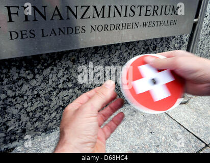 ILLUSTRATION - In einer inszenierten Szene wird eine CD mit einer Schweizer Flagge bedruckt ist vor dem Finanzministerium in Düsseldorf, Deutschland, 15. Juli 2012 übergeben. Die angebliche Übernahme durch die deutschen Bundesland Nordrhein Westfalen eine andere CD aus der Schweiz mit reichen Germans  Bankverbindung als Teil der Bemühungen um Steuerhinterzieher zu identifizieren hat die Schweizer verärgert. Schweizer Stockfoto