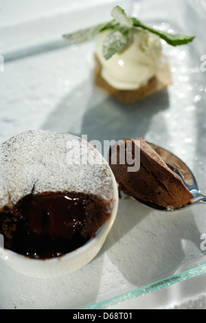 Schokoladendessert Elch in einem weißen Töpfchen auf einer Glasplatte mit Vanille-Eis Kugel gefrostet Stockfoto