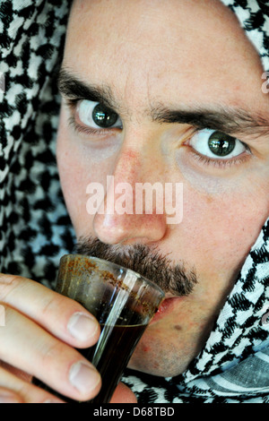 Ein Portrait eines jungen arabischen Mannes trägt ein Kaffiyehs Dirinkling Kaffee. Model-Release verfügbar Stockfoto