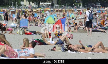 Urlauber am Strand in Travemünde, Deutschland, 23. Juli 2012 liegen. Sie haben nicht alle noch bewohnt, aber die Zahl der Besucher hat am ersten sonnigen Tag nach einer langen Zeit des regnerischen Wetters bereits merklich erhöht. Meteorologen prognostizieren, dass Sonnenschein und steigenden Temperaturen für die Ostsee Küste bis 26. Juli 2012. Foto: MARKUS SCHOLZ Stockfoto