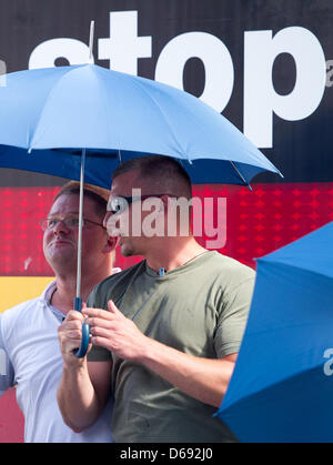 Anhänger der rechtsextremen nationalen demokratischen Partei (NPD) versuchen, den Vorsitzenden der NPD Holger Apfel (L) aus Eiern geworfen von Gegendemonstranten mit Sonnenschirmen in Frankfurt Main, Deutschland, 27. Juli 2012 zu schützen. Apfel steht vor einem NPD-LKW in Partei Parolen bedeckt. Mehrere hundert Demonstranten, die verhindert, dass die NPD Roemerberg Quadrat mit einem Lautsprecher geben könnte Stockfoto