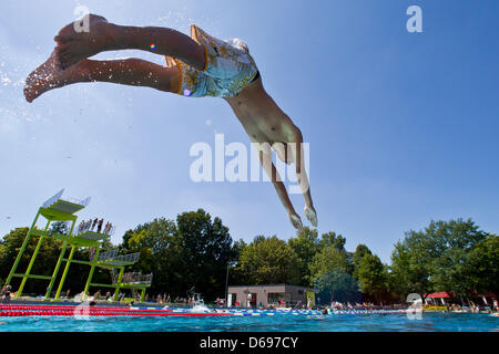 Ein Junge springt in ein Freibad in Nürnberg, 1. August 2012. Sommerliche Temperaturen von bis zu 30 Grad Celsius lockte viele Besucher an den Open-Air-Pool. Foto: DANIEL KARMANN Stockfoto