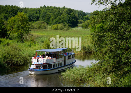 Touristen genießen die Aussicht auf einen Kanal auf einem Ausflugsschiff in Templin, Deutschland, 1. August 2012. Naturpark Uckermarkische gesehen, als auch die Feldberger Seenlandschaft, die beide von Berlin über die Havel erreicht werden kann, sind ein Paradies für Amateur-Kapitäne. Brandenburg verfügt über mehr als 3.000 Seen und rund 30.000 km Fließgewässer, davon 1.600 einsetzbar durch Motorboote ein Stockfoto