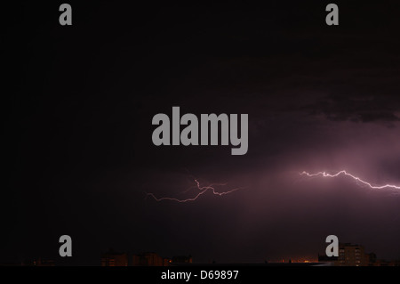 Ein kräftiger Blitzschlag erleuchtet den Nachthimmel, der in einer dramatischen Darstellung der Energie der Natur festgehalten wird. Das Bild zeigt den Kontrast zwischen dem hellen Blitz des Blitzes und dem dunklen, wolkengefüllten Himmel. Stockfoto